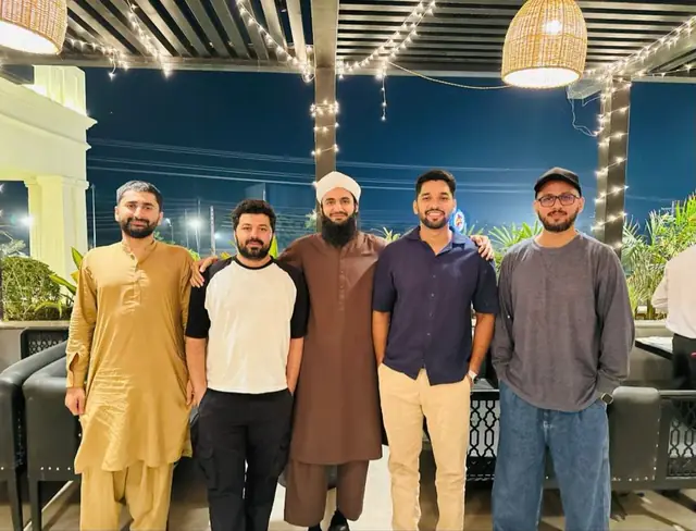 Five friends standing together on a rooftop terrace at night